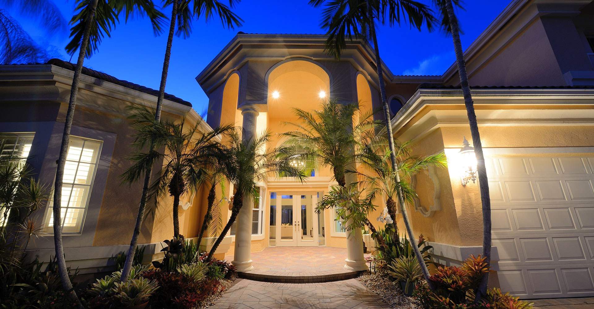 Luxury home at dusk framed by palm trees