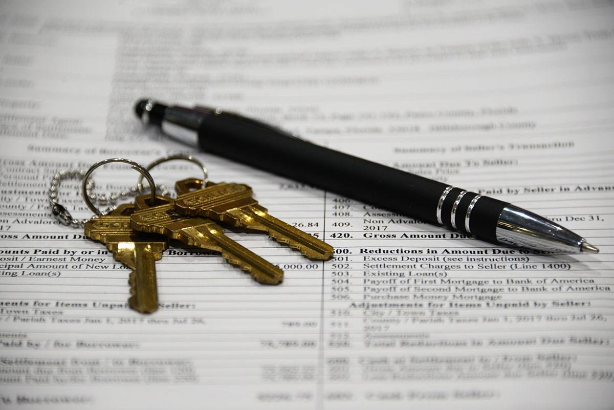 House keys and a pen resting on a signed closing statement